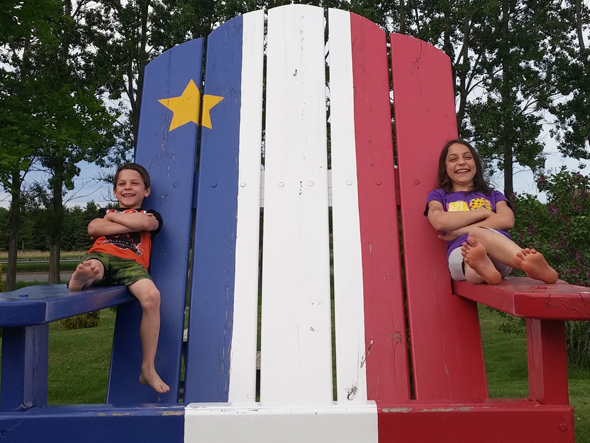 Blogue - Acadiens - Enfants et chaise Les enfants s'amusent sur la chaise acadienne.